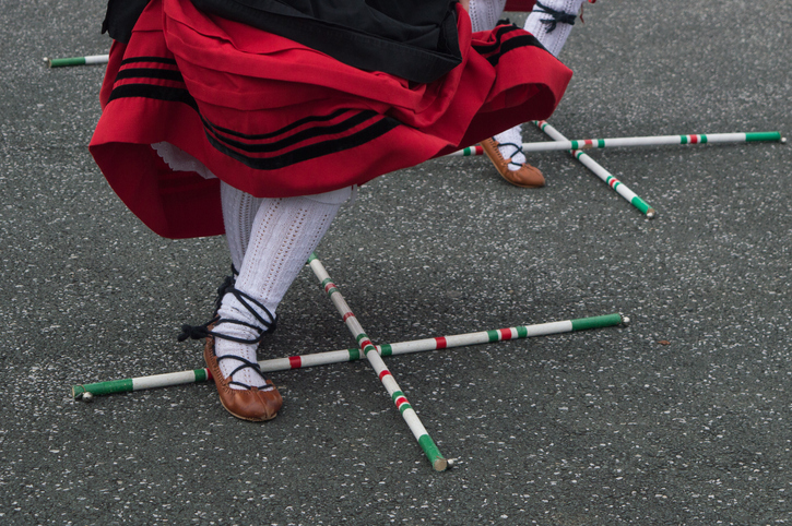 Basque dance in traditional costume with cross sticks on the floor
